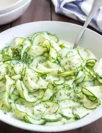 Omas Gurkensalat mit Schmand und Dill in einer weißen Schüssel serviert