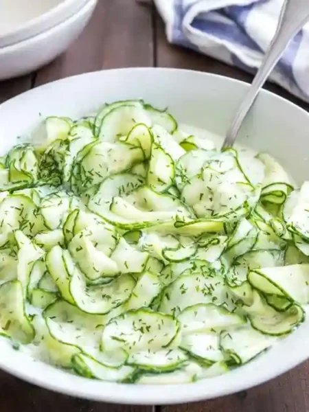 Omas Gurkensalat mit Schmand und Dill in einer weißen Schüssel serviert