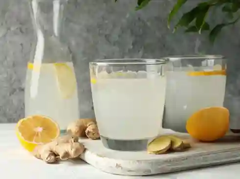 Ingwer Shot Thermomix in Flasche und Gläsern, serviert mit Zitronen und Orangen.