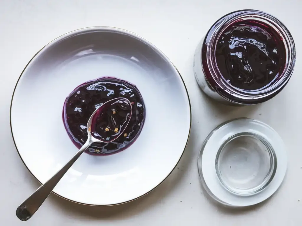 Zwetschgenmarmelade mit Rum auf einem rustikalen Teller, begleitet von einem Glas Marmelade.