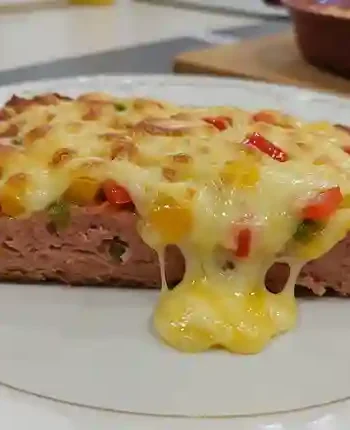 Leberkäse Rezepte Überbacken - Überbackener Leberkäse auf einer dunklen Platte, garniert mit Microgreens.