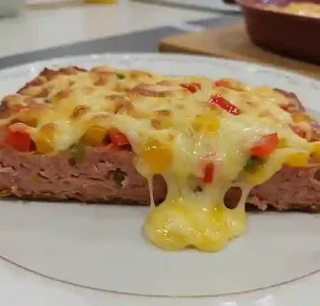 Leberkäse Rezepte Überbacken - Überbackener Leberkäse auf einer dunklen Platte, garniert mit Microgreens.