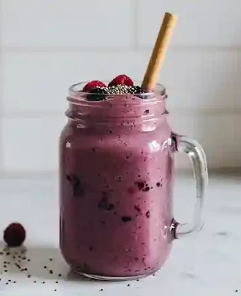 smoothie mit wasser statt milch : Leuchtend violetter Smoothie im klaren Glas, getoppt mit Chiasamen und frischen Beeren.