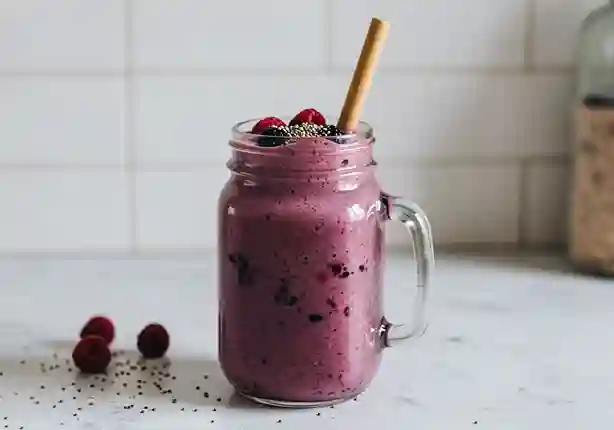 smoothie mit wasser statt milch : Leuchtend violetter Smoothie im klaren Glas, getoppt mit Chiasamen und frischen Beeren.