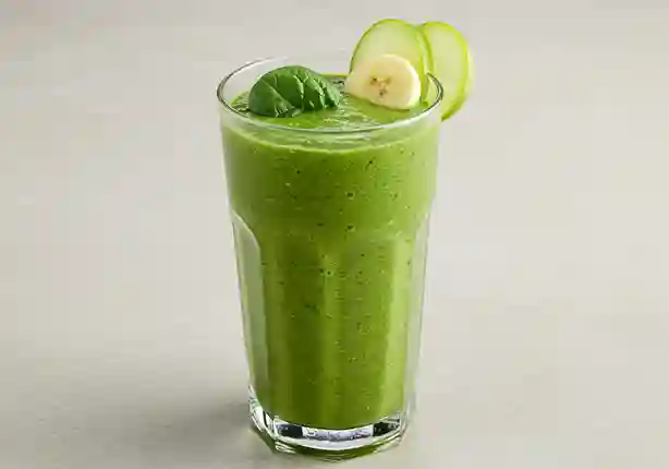 Ein hoher, klarer Glas gefüllt mit einem leuchtend grünen Spinat Smoothie, garniert mit einem frischen Spinatblatt und Apfelscheibe.