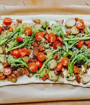 Flammkuchen Vegan mit buntem Gemüse, frischen Tomaten und knusprigem Teig auf einem Backblech