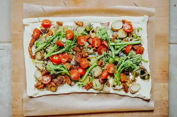 Flammkuchen Vegan mit buntem Gemüse, frischen Tomaten und knusprigem Teig auf einem Backblech