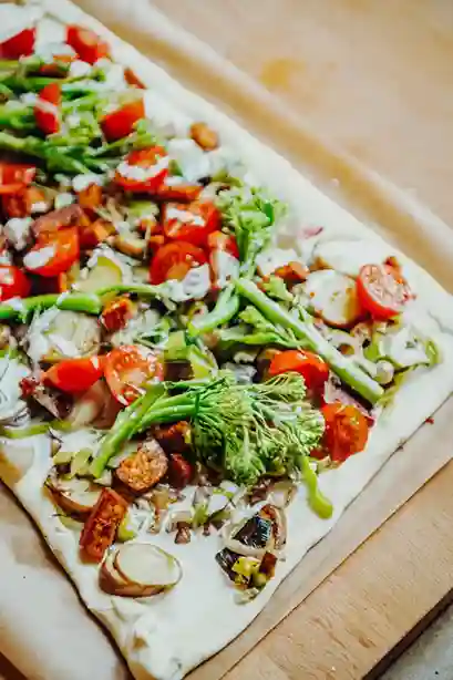 Frischer Flammkuchen Vegan mit buntem Gemüsebelag auf einem Backblech vor dem Backen