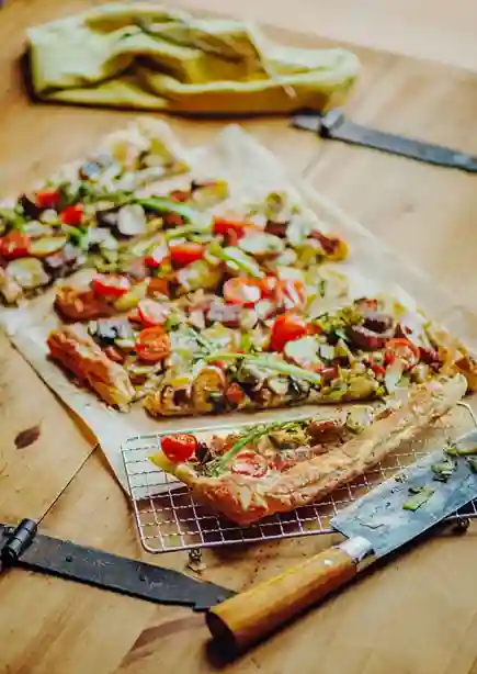 Frisch gebackener Flammkuchen Vegan mit buntem Gemüse, knusprigem Rand und einem rustikalen Holzhintergrund.