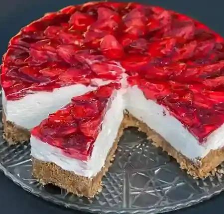 Ein köstlicher Erdbeerkuchen ohne Backen mit Keksboden und Mascarpone, verziert mit frischen Erdbeeren und rotem Tortenguss, auf einer eleganten Glasplatte serviert.