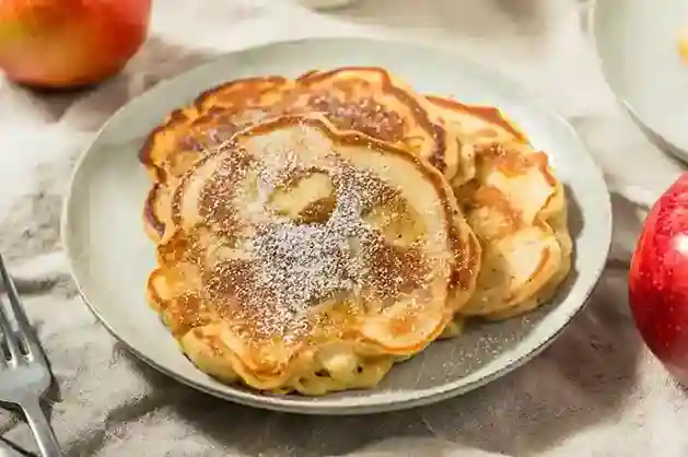 Goldbraune Apfelpfannkuchen nach Omas Rezept, serviert mit Puderzucker – ein einfaches und leckeres Apfelpfannkuchen Rezept.