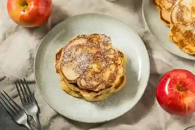 Ein Stapel goldbrauner Apfelpfannkuchen mit Puderzucker – das perfekte Apfelpfannkuchen Rezept für ein süßes Frühstück oder Dessert.