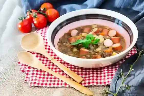 Linsensuppe Schnellkochtopf – Herzhafte Linsensuppe mit Würstchen, serviert mit frischen Kräutern.