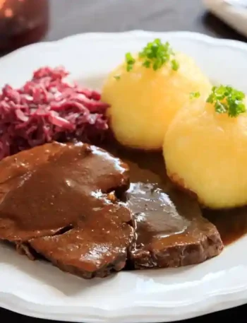 Rezept Großmutters Sauerbraten im Backofen mit Rotkohl und Klößen – ein traditionelles deutsches Gericht, das langsam geschmort wird.