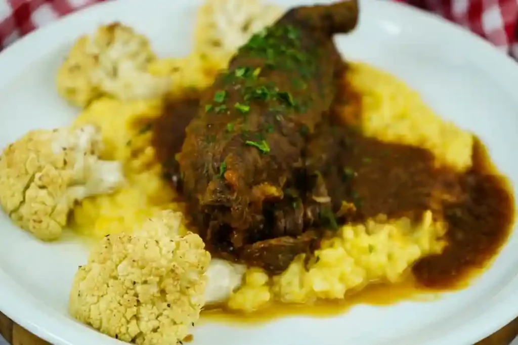 Rouladen im Schnellkochtopf serviert mit cremigem Kartoffelpüree, geröstetem Blumenkohl und einer herzhaften Sauce, garniert mit frischer Petersilie.