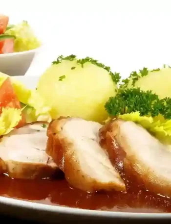 Bayerischer Krustenbraten mit Kartoffelknödeln, frischem Salat und dunkler Bratensoße – die perfekten Beilagen zum Krustenbraten.