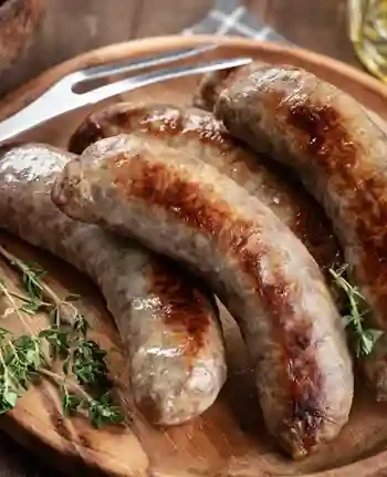 Grobe Bratwurst perfekt gebraten auf einem rustikalen Holzteller mit frischen Kräutern serviert.