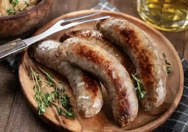 Grobe Bratwurst perfekt gebraten auf einem rustikalen Holzteller mit frischen Kräutern serviert.