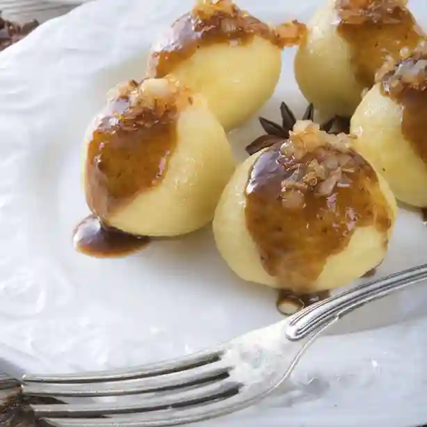 Kartoffelklöße mit goldbrauner Sauce für Knödel und knusprigen Zwiebeln, serviert auf einem weißen Teller.