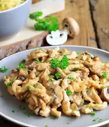 Spätzle mit Hähnchen in cremiger Soße mit Pilzen, serviert auf einem Teller, garniert mit frischer Petersilie.