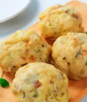 Frische vegetarische Knödel auf einem Holzbrett mit Kräuterdekoration.