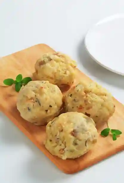 Knödel vegetarisch – Hausgemachte vegetarische Klöße auf einem Holzbrett mit frischen Kräutern.