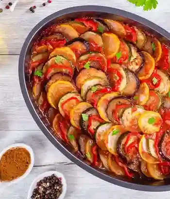 Ratatouille Rezept mit geschichtetem Gemüse in einer Auflaufform, servierfertig auf einem hellen Tisch