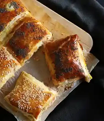 Blätterteig gefüllt mit Schinken und Käse auf einem Holzbrett serviert