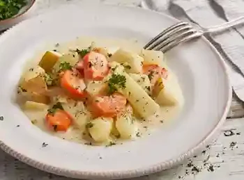 Cremiges Kohlrabigemüse mit Kartoffeln und Möhren serviert auf einem weißen Teller