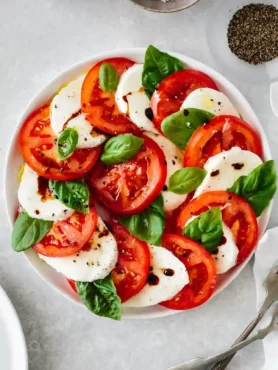 Caprese Salat mit Tomaten, Mozzarella und frischen Basilikumblättern, gewürzt mit Gewürzen für Tomate Mozzarella Salat.