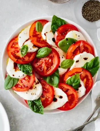Caprese Salat mit Tomaten, Mozzarella und frischen Basilikumblättern, gewürzt mit Gewürzen für Tomate Mozzarella Salat.