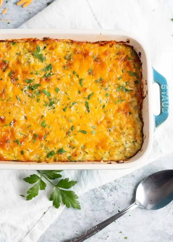 Zucchini Auflauf mit Käse überbacken, frisch aus dem Ofen, mit geschmolzenem Käse und frischem Grün garniert.