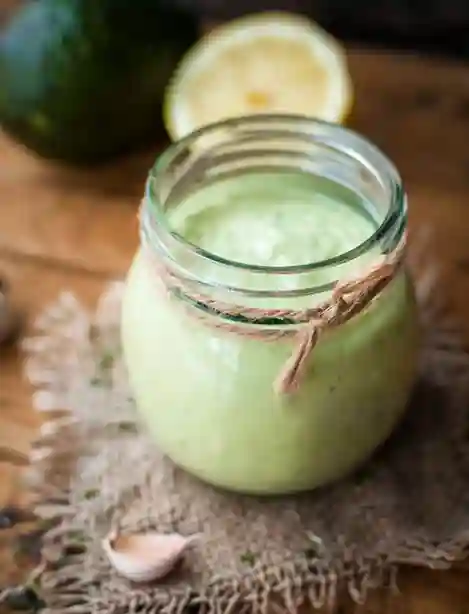 Frisches Avocado Dressing für Salat in einem Glas mit einem Hauch Zitronensaft und Knoblauch, ideal für Salate.