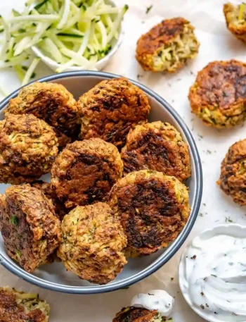 Knusprig gebackene kalorienarm Zucchinipuffer mit Haferflocken und Käse serviert mit frischem Dip.