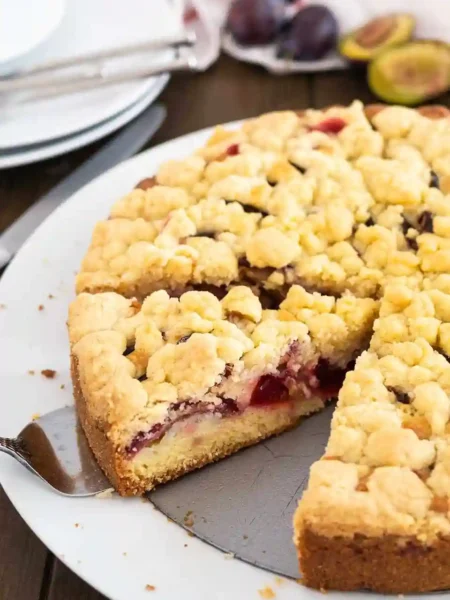 Omas Zwetschgenkuchen mit Streusel auf weißem Kuchenteller serviert