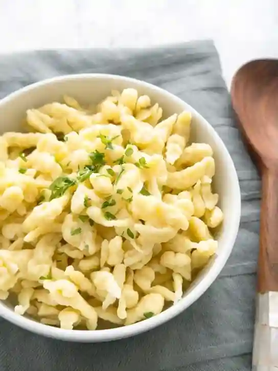 spätzleteig rezept – fertige Spätzle aus klassischem Teig, serviert mit frischen Kräutern