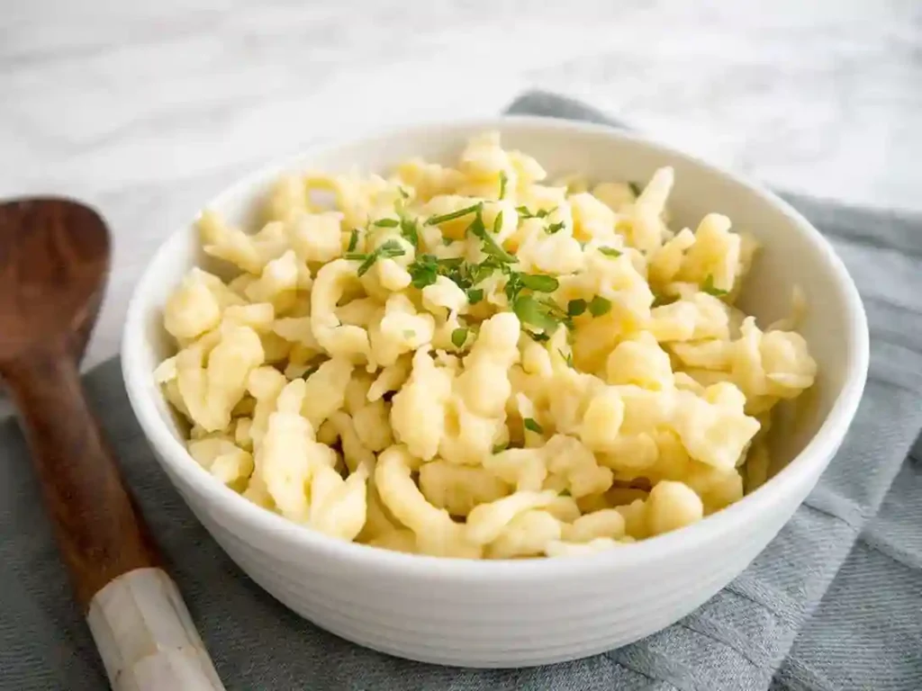 rezept spätzle – frisch gekochte Spätzle mit Kräutern in einer weißen Schüssel serviert