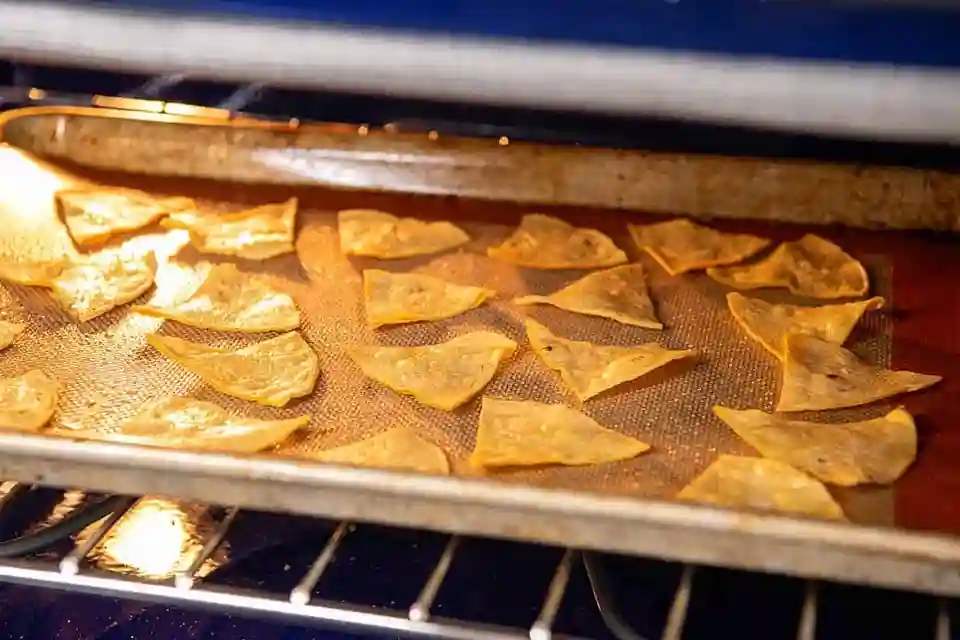 Tortilla Chips selber machen: Tortilla chips baking in the oven on a baking tray.