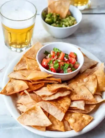 Tortilla Chips served with fresh salsa and guacamole, accompanied by beer.