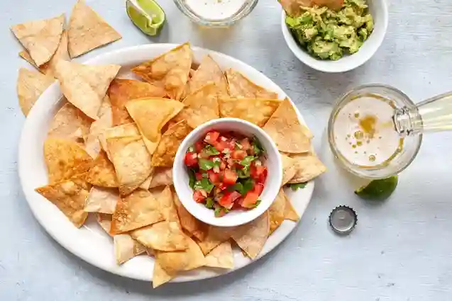 Tortilla Chips served with fresh salsa, guacamole, and a refreshing drink.