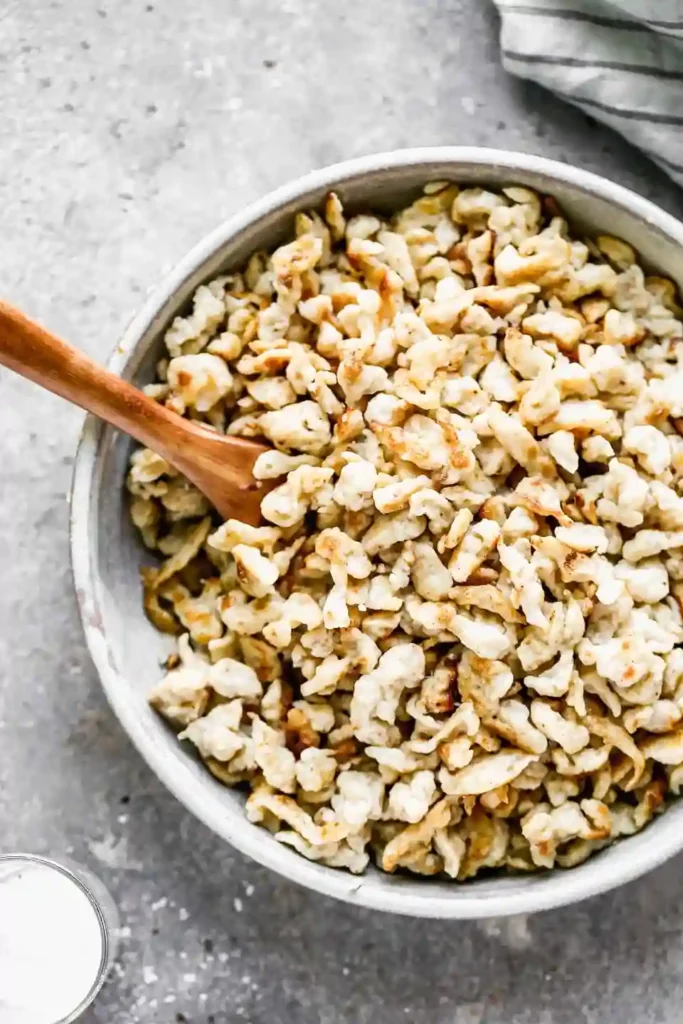 rezept spätzle – gebratene Spätzle in einer Schüssel mit Holzlöffel serviert