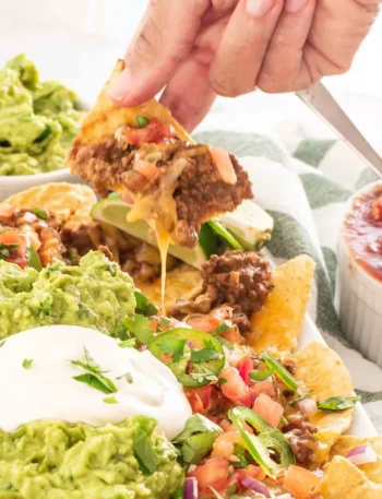 Überbackene Nachos mit Käse und Hackfleisch, serviert mit frischer Guacamole, Salsa und saurer Sahne.