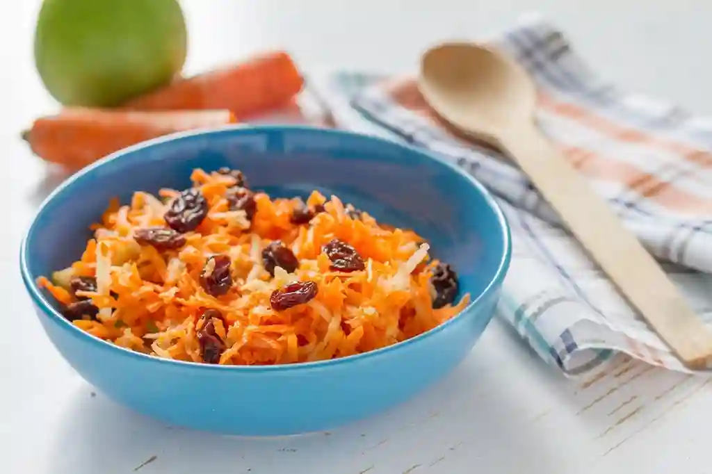 Bunte Schale mit Omas Möhrensalat mit Apfel und Zitrone und Rosinen