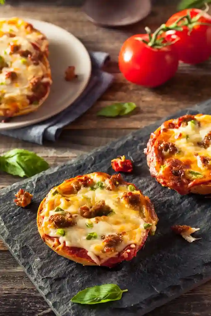Pizzabrötchen selbst gemacht mit Käse, Tomaten und Rinderschinken auf einem Servierbrett