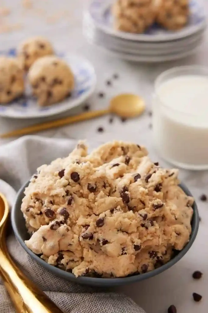 Schale mit essbarem Keksteig – cookie dough rezept mit Schokodrops und Milch im Hintergrund.