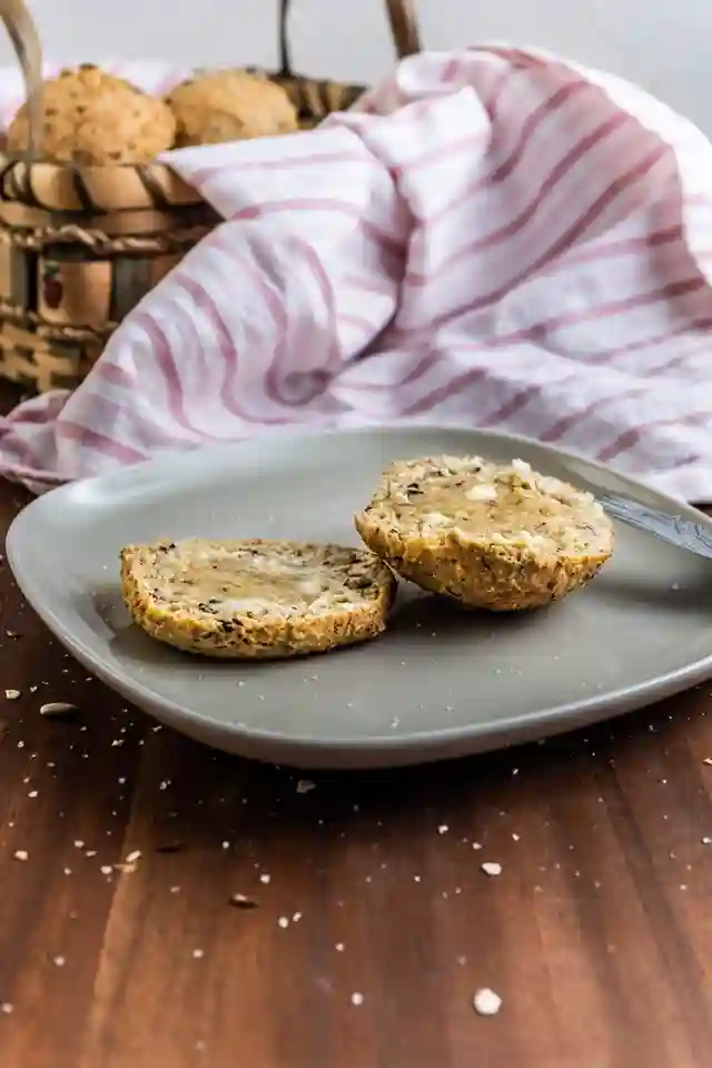 Aufgeschnittene Sonntagsbrötchen ohne Hefe mit Butter auf einem Teller, im Hintergrund ein Brotkorb