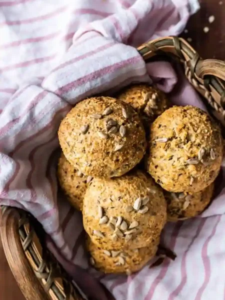 Frisch gebackene Sonntagsbrötchen ohne Hefe mit Haferflocken, Quark und Körnern in einem Brotkorb auf einem Küchentuch serviert