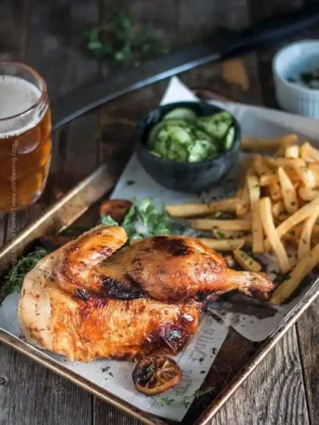 Halbes Hähnchen im Backofen mit knuspriger Haut, serviert mit Pommes und Gurkensalat auf einem Blech – traditionell wie vom Biergarten oder Oktoberfest.