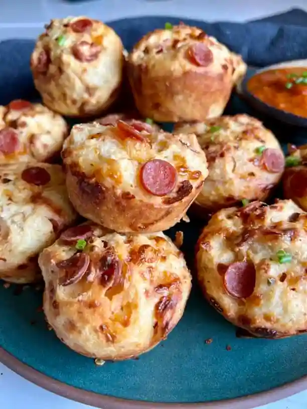 Pizza Muffins mit Peperoni, knusprig gebacken auf grünem Teller – herzhafte Pizzamuffins schnell und einfach zubereitet.