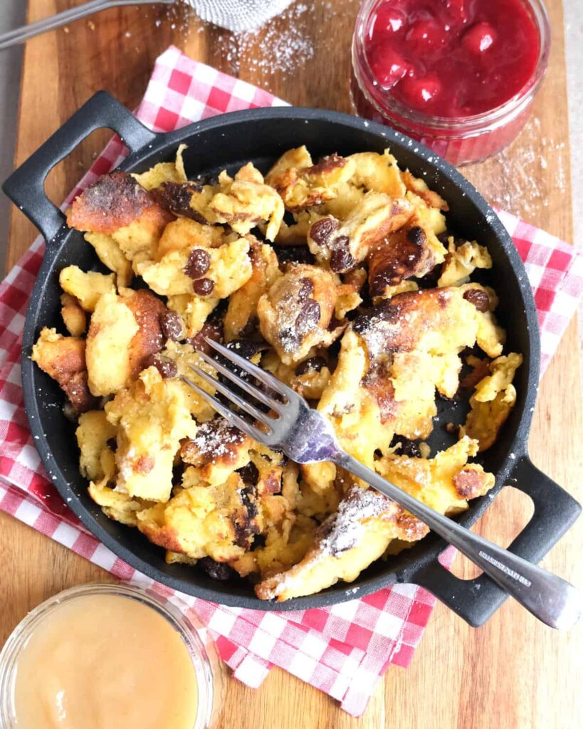 Original Kaiserschmarrn Rezept mit Rosinen und Apfelmus in rustikaler Servierpfanne